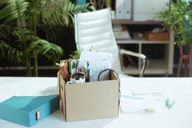 Yeni bir iş. Modern yeşil ofiste masa ve karton kutuda kişisel eşyalar..