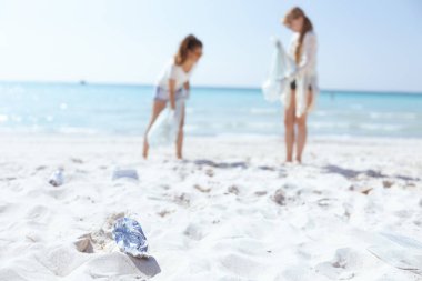 Plajdaki çöplere ve çöp torbası toplayan çevrecilere yakından bakın..