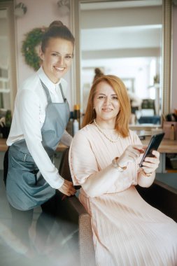 Modern güzellik stüdyosunda akıllı telefonu olan bir kadın kuaför..