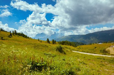 Dolomitlerde yaz zamanı. Dağlarla, tepelerle, bulutlarla, çayırlarla ve ağaçlarla dolu bir manzara.
