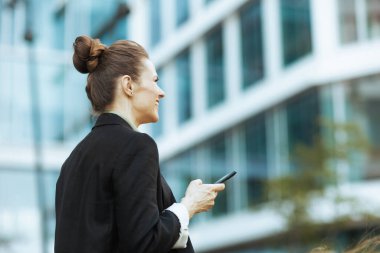 İş merkezinin yanında çalışan siyah ceketli, akıllı telefon kullanan modern bir kadın tarafından görülmüş..