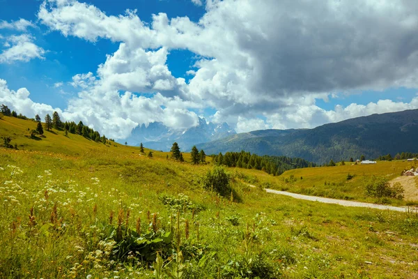 Dolomitlerde yaz zamanı. Dağlarla, tepelerle, bulutlarla, çayırlarla ve ağaçlarla dolu bir manzara.