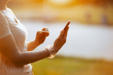 Yaz zamanı. Akıllı telefon uygulaması kullanarak beyaz tişörtlü kadına yaklaş..