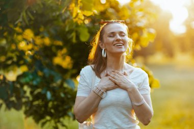 Yaz zamanı. Gülümseyen, beyaz tişörtlü, göğsü açık modern bir kadın..