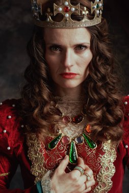 Koyu gri arka planda taçlı kırmızı elbiseli ortaçağ kraliçesi..