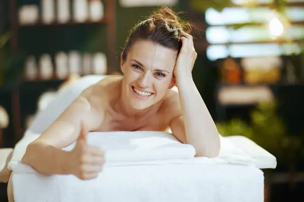 卫生保健时间 快乐的现代女性躺在按摩室里 竖起大拇指 躺在按摩床上 — 图库照片