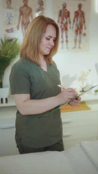 卫生保健时间 带剪贴板的按摩柜中微笑的女性按摩师 — 图库视频影像