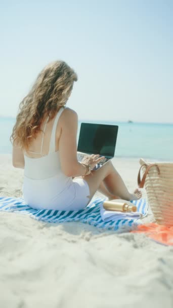 从现代女子身后看到 在海滨带着稻草袋 手提电脑 空白屏幕和条纹毛巾 — 图库视频影像
