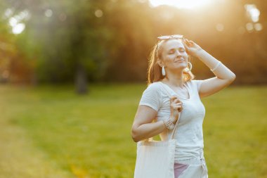 Yaz zamanı. Şehir parkındaki çayırda çantalı, beyaz tişörtlü 40 yaşında, rahat, zarif bir kadın..