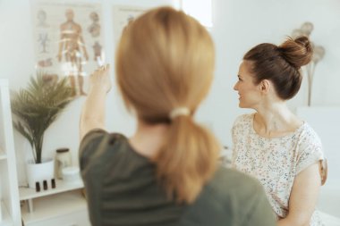 Sağlık hizmeti zamanı. Kadın masaj terapistinin arkasından müşteriyle birlikte masaj dolabında görülmüş..