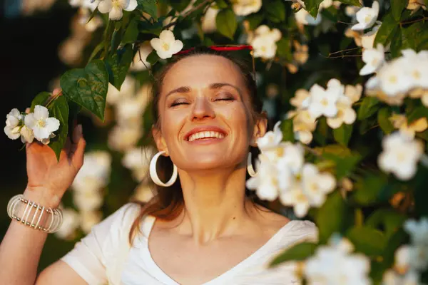 夏天的时候快乐的年轻女子 身穿白衬衫 紧挨着开花的树 — 图库照片