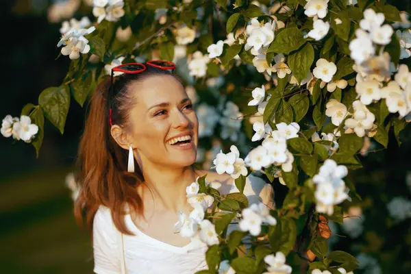 夏天的时候中年妇女笑着 白衬衫紧挨着开花的树 — 图库照片