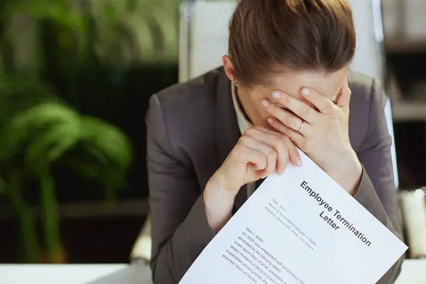 stock image New job. Closeup on modern woman worker in modern green office in grey business suit with employee termination letter.