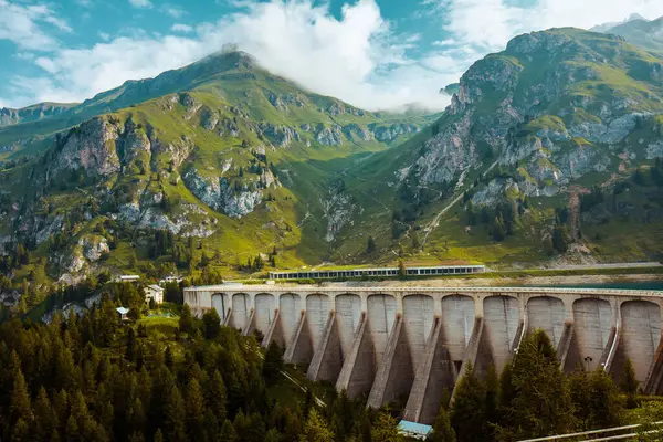 Dolomitlerde yaz zamanı. Dağlı, bulutlu, ağaçlı ve barajlı manzara.