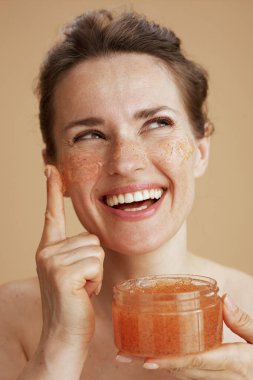 Mutlu orta yaşlı kadın bej arka planda izole edilmiş yüz fırçası ile.