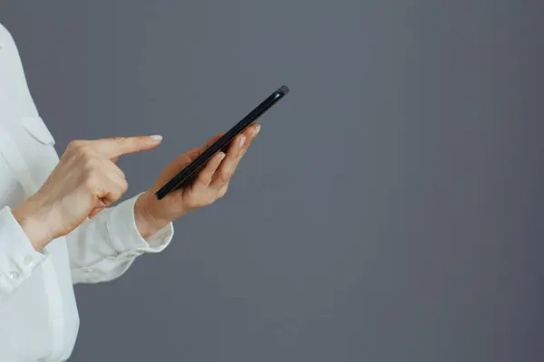 使用在灰色背景下隔离的智能手机应用程序为白衬衫女雇员提供的服务 — 图库照片