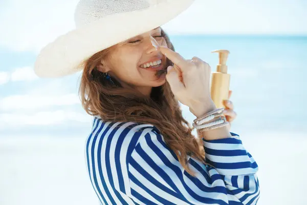 快乐的现代女性在沙滩上用防晒霜 免版税图库照片