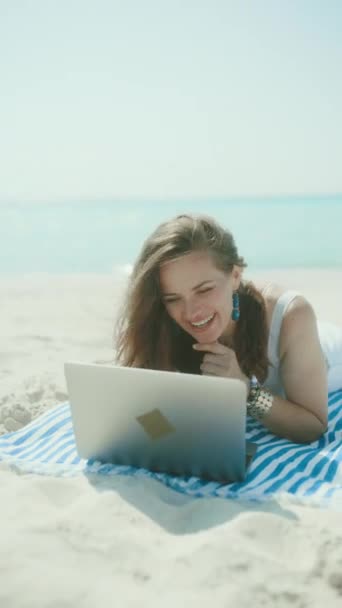带着稻草袋 笔记本电脑和条纹毛巾在海滩上快乐而时尚的中年妇女 — 图库视频影像