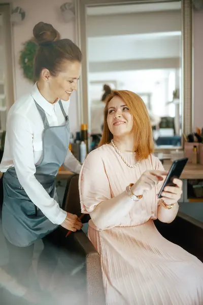 Kvinnlig Frisör Modern Hårstudio Med Klient Med Smartphone Stockbild