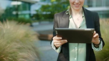 Mutlu orta yaşlı kadın işçi iş bölgesinde siyah ceketli tablet bilgisayar kullanıyor..