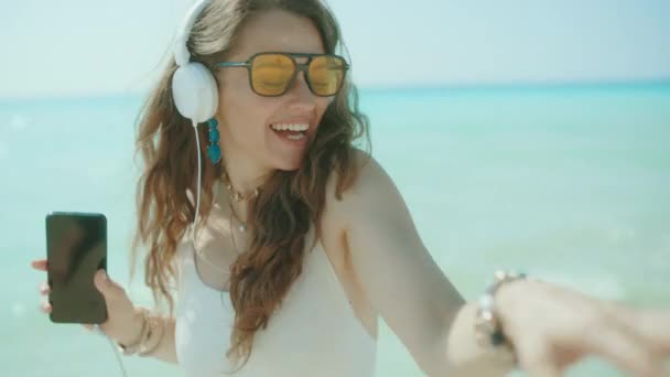 Χαρούμενη Κομψή Γυναίκα Στη Θάλασσα Smartphone Χορεύει Και Ακούει Μουσική — Αρχείο Βίντεο