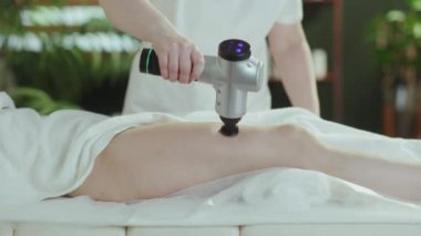 Sağlık hizmeti zamanı. Masaj kabinindeki masaj terapistine yakın çekim. Masaj tabancası müşterilere bacak masajı yapıyor..