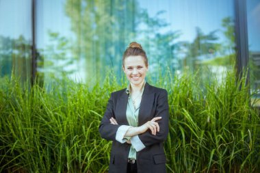 Ofis yakınında, kollarını kavuşturmuş siyah ceketli mutlu modern kadın işçi..