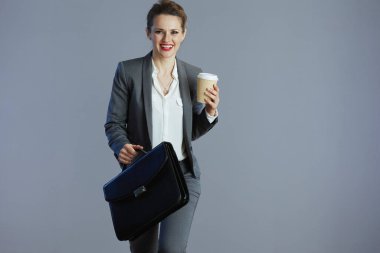 Gri takım elbiseli, gri çantalı, küçük işletme sahibi 40 yaşında, güler yüzlü bir kadın..