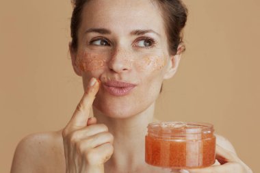 Gülümseyen genç bir bayan, bej arka planda yüz ovucu.