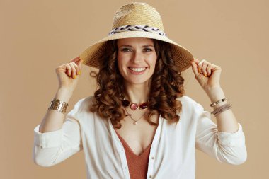 Plaj tatili Beyaz bluzlu mutlu bir bayan ve bej arka planda şortlu yaz şapkalı..