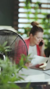 Sürdürülebilir iş yeri. İşte gülümseyen modern muhasebeci kadına yakın çekim. Elektrikli fan ve dizüstü bilgisayarla..