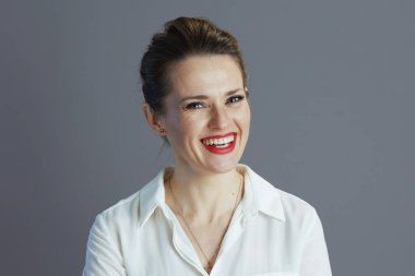 Kırk yaşında, beyaz bluzlu zarif bir kadın işçi gri arka planda izole edilmiş..