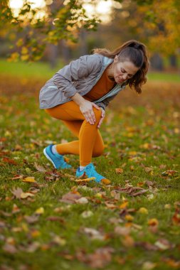 Merhaba sonbahar. Mutsuz, orta yaşlı, formalı bir kadın parkta ayak ağrısı çekiyor..