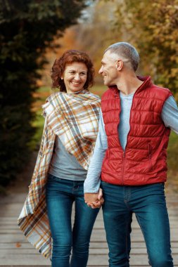 Merhaba sonbahar. Gülümseyen şık bir çift parkta yürüyor..