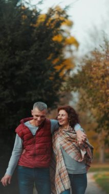 Merhaba sonbahar. Gülümseyen şık bir çift parkta yürüyor..