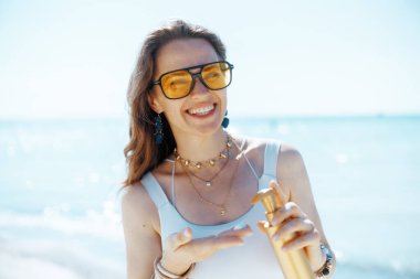 Deniz kıyısında, güneş kremiyle gülümseyen modern bir kadın..