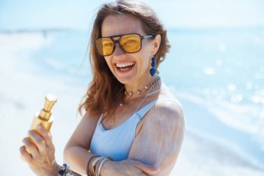 Deniz kıyısında güneş kremiyle gülümseyen zarif bir kadın..