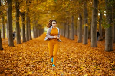 Merhaba sonbahar. Parkta spor kıyafetleriyle koşan fit bir kadın portresi..