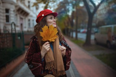 Merhaba sonbahar. Mutlu, kırmızı şapkalı, güz yaprakları ve atkısı olan modern kadın..