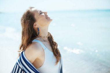 Okyanus kıyısında mutlu zarif bir kadın. Huzurun tadını çıkarıyor..