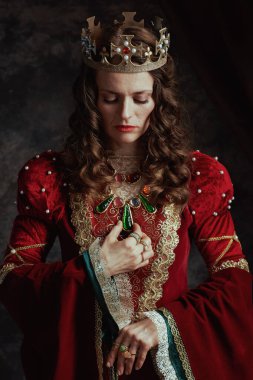 Koyu gri arka planda taçlı kırmızı elbiseli ortaçağ kraliçesi..
