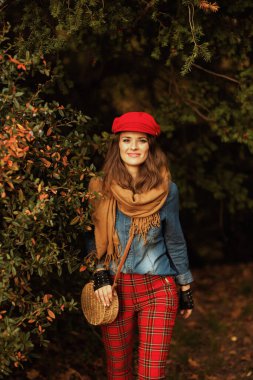 Merhaba sonbahar. Mutlu modern 40 yaşında kot gömlekli, kırmızı şapkalı, eşarplı, eldivenli ve çantalı bir kadın..