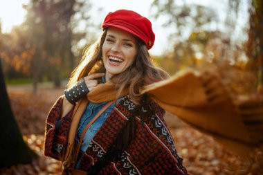 Merhaba sonbahar. Parkta eşarplı, kırmızı şapkalı, gülümseyen genç bir kadın..