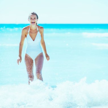 Sahilde dalgalar ile oynarken mutlu bir genç kadın