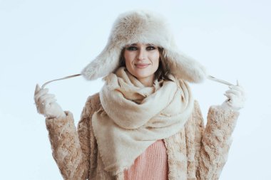 Beyaz eldivenli beyaz arka planda, kışlık ceketli ve kürklü mutlu orta yaşlı kadın..