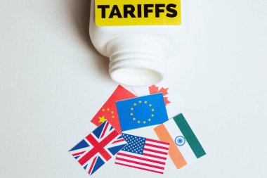 Çin, AB, ABD, Hindistan, Birleşik Krallık ve Kanada 'nın bayrakları etrafa saçılmış cesur bir' TARIFFS 'etiketli beyaz şişenin yakın çekimi, küresel ticaret anlaşmazlıklarının kaosunun.