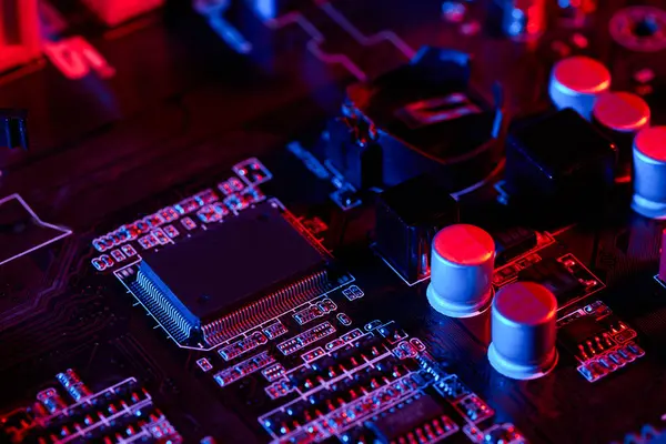 Kırmızı ve maviyle aydınlatılmış çipler, kapasitörler ve devrelerle bir bilgisayar anakart yüzeyine yakın çekim yapmak, yüksek teknolojili, karmaşık bir elektronik tasvir yaratıyor..