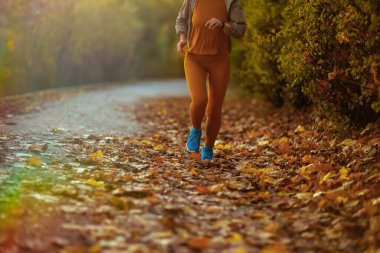 Merhaba sonbahar. Parkta koşan spor elbiseli bir kadına yakın çekim..