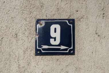 Yıpranmış, köhne, metal plakalı, üzerinde 9 numara olan sokak adresi.
