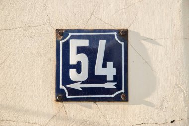 Yıpranmış kare metal plaka numarası 54 olan sokak adresi.